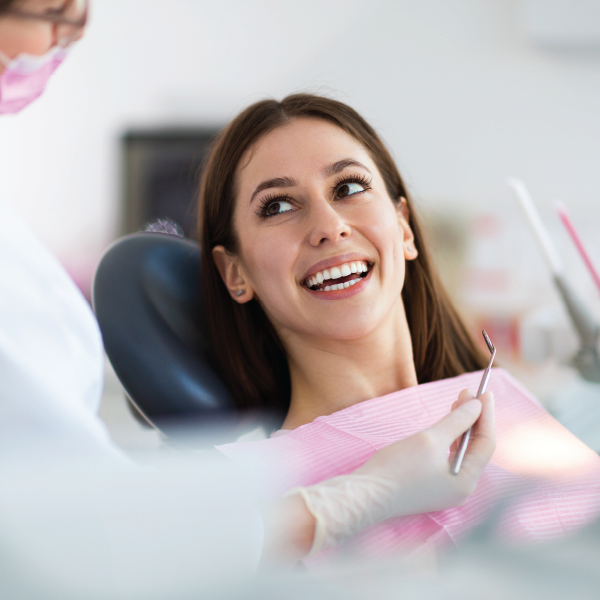  A woman in a dentist chair smiling and looking at the dentist.