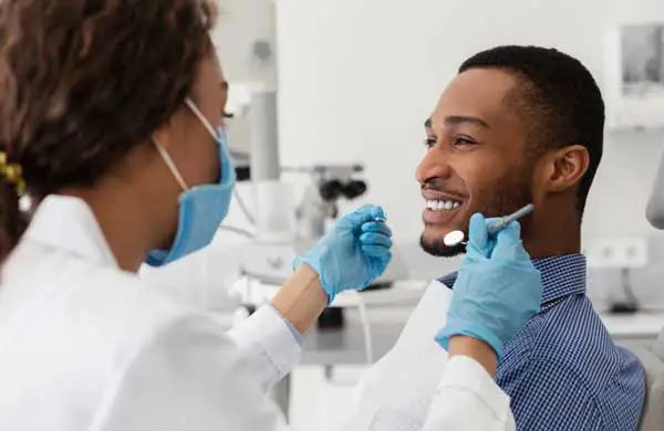 A male patient smiling as the dentist examines his teeth.